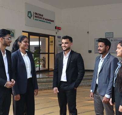 Students in formal attire standing and interacting near the entrance of Kirloskar Institute of Management building