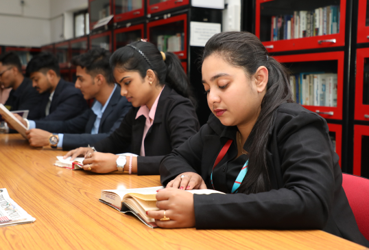 Management students at KIM Harihar Campus library dressed professionally reading and reviewing books
