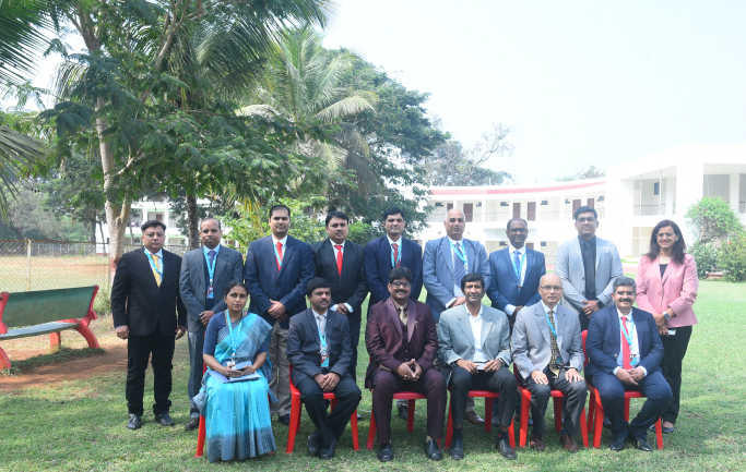 Faculty and staff group photograph on campus lawn at Kirloskar Institute of Management