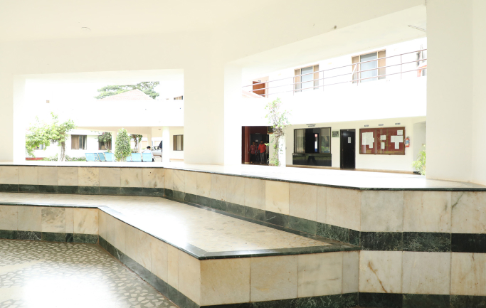 Open campus corridor with seating area and academic building interiors at Kirloskar Institute of Management
