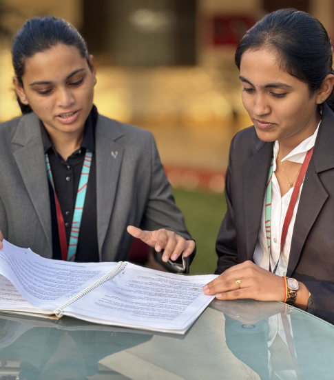 Female management students dressed professionally at KIM Harihar campus dicussing and reviewing their academic notes