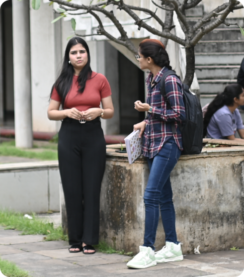Two students talking near campus walkway with notebooks and backpack