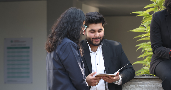 Professionally dressed management students at KIM Pune reviewing and discussing book content