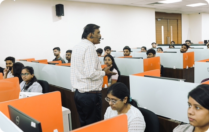 Faculty member interacting with students in a computer lab session at KIM Pune